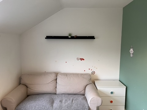 Loft room with old sofa and marked walls before renovation in Oxfordshire